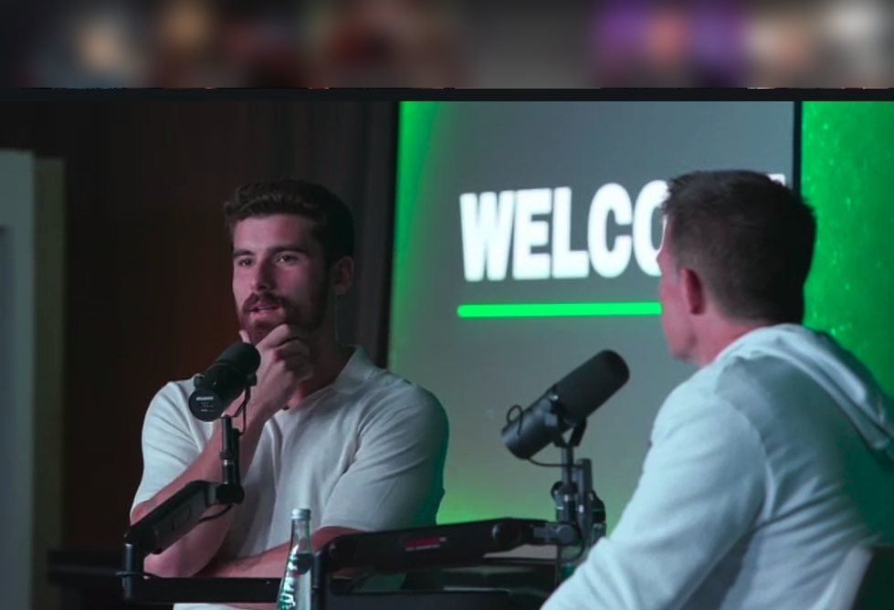 Inside the July 22, 2026 Side Hustle Summit partner briefing — Iman Gadzhi and Russell Brunson on stage in front of a Welcome screen, attendee gallery blurred for privacy
